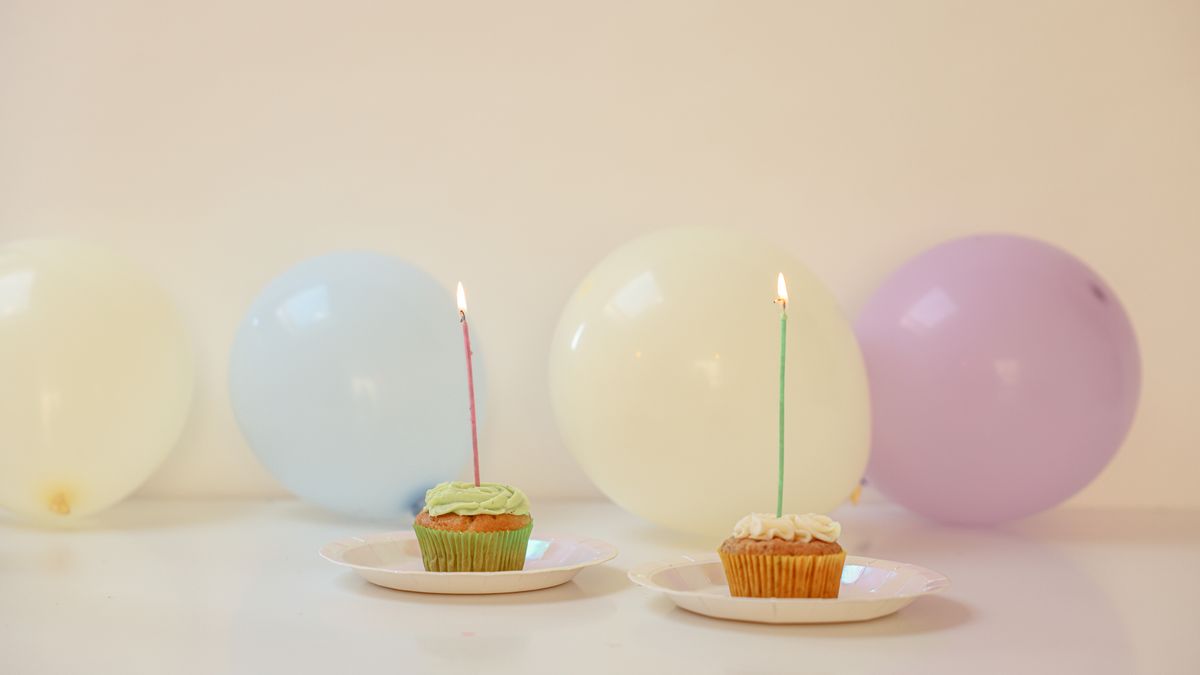 Pastel balloons and birthday cupcakes with lit candles