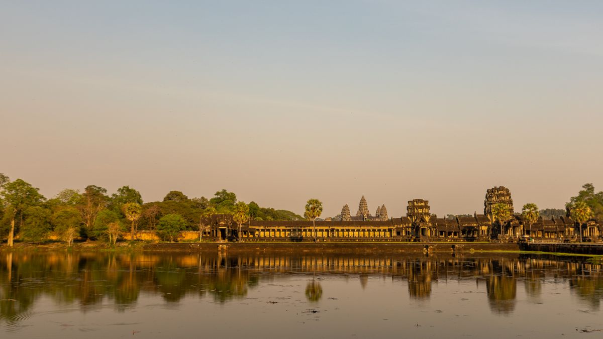 Angkor Wat temple reflected in calm water at golden hour