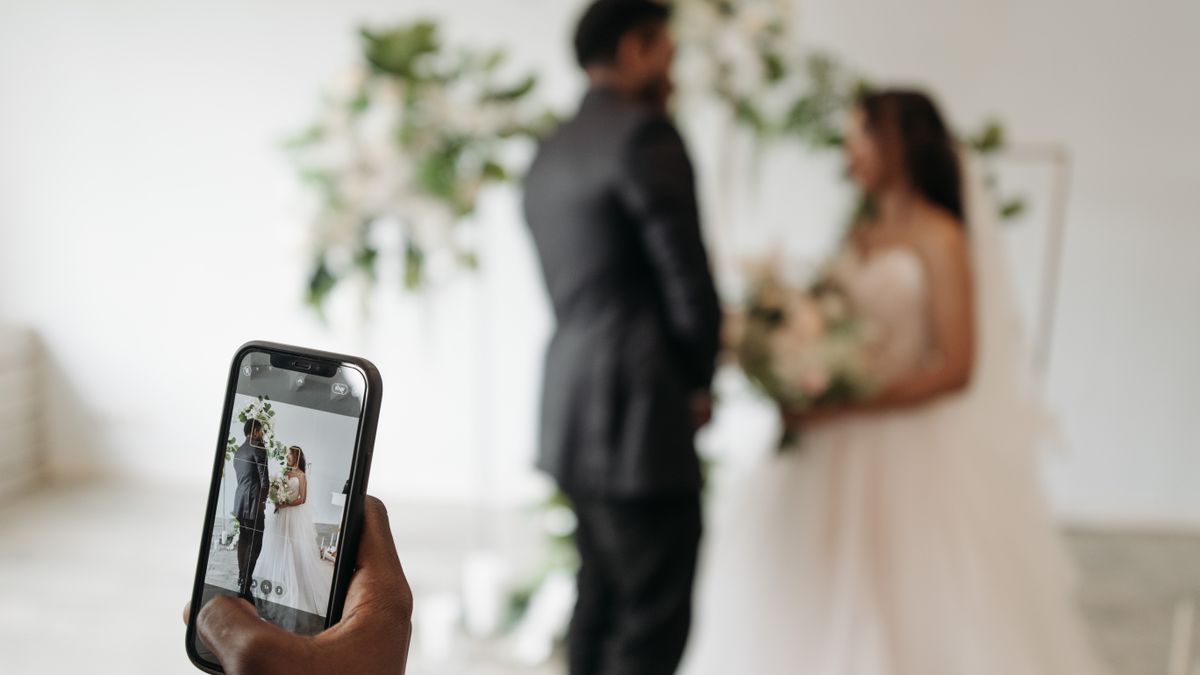 A guest photographing a wedding couple on a smartphone